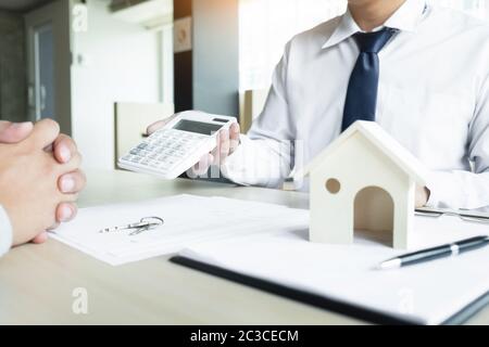 Immobilienmakler, der seinen Kunden den Kaufpreis auf einem Rechner anzeigt Stockfoto