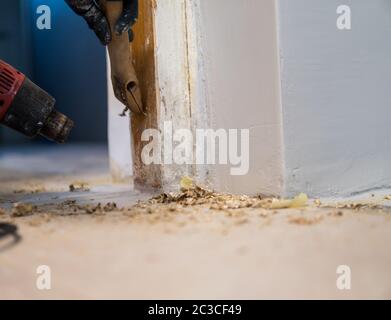 Details zum Entfernen alter weißer Farbe aus dem Türrahmen mit Heißluftpistole und Abstreifer Stockfoto