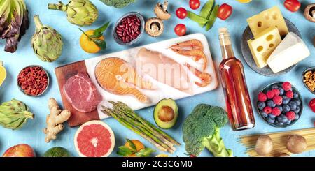 Essen, Panorama über dem Kopf auf blauem Hintergrund. Fleisch, Fisch, Meeresfrüchte, Geflügel, Wein, Käse, Pilze, Nudeln, Nüsse, Obst und Gemüse Stockfoto