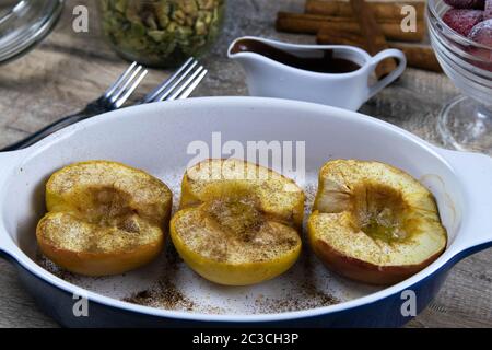 Karamellisierte Äpfel mit Honig und Zimt in einer Tonschale auf hellem Holzhintergrund. Draufsichten Stockfoto