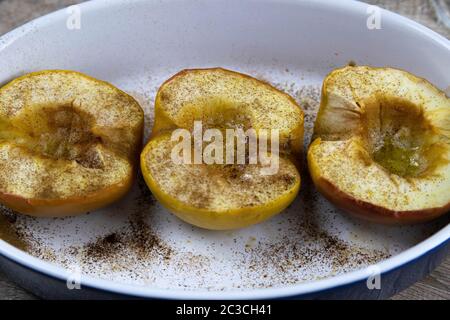 Karamellisierte Äpfel mit Honig und Zimt in einer Tonschale auf hellem Holzhintergrund. Draufsichten Stockfoto