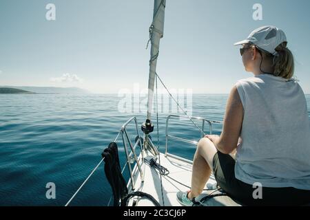 Frau, die auf den Schiffen sitzt, beugt sich und genießt die Jachtreise. Segel-, Segelsport- und Reisekonzept. Stockfoto
