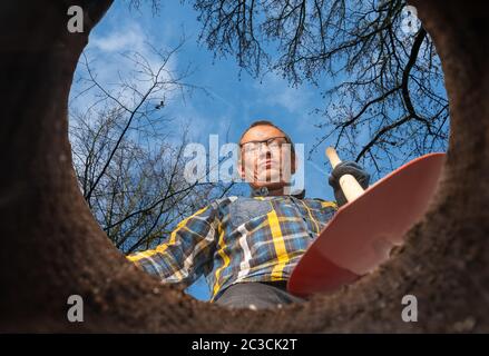 Ein Mann mit einer Schaufel steht an einem Loch im Boden Stockfoto