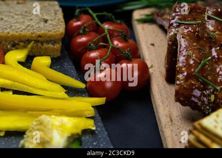 Rippen unter Honigsauce auf einem Holzbrett neben Tomaten, Glockenpapier und Brot. Draufsichten Stockfoto