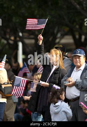 Austin Texas, USA, November 11 2014: Zuschauer winken während der jährlichen Parade des Veterans Day in Austin entlang der Congress Avenue mit kleinen amerikanischen Flaggen. ©Marjorie Kamys Cotera/Daemmrich Photography Stockfoto