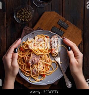 Spaghetti mit Stücken von frischem Thunfisch, Tomaten und Kapern auf einem dunklen Hintergrund Stockfoto