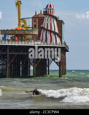 Brighton UK 19. Juni 2020 - Surfer versuchen an einem sonnigen, aber luftigen Nachmittag entlang der Südküste eine Welle am Brighton Palace Pier zu fangen. Das Wetter wird voraussichtlich viel wärmer werden nächste Woche mit Temperaturen voraussichtlich 30 Grad in Teilen des Südostens erreichen : Credit Simon Dack / Alamy Live News Stockfoto