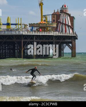 Brighton UK 19. Juni 2020 - Surfer versuchen an einem sonnigen, aber luftigen Nachmittag entlang der Südküste eine Welle am Brighton Palace Pier zu fangen. Das Wetter wird voraussichtlich viel wärmer werden nächste Woche mit Temperaturen voraussichtlich 30 Grad in Teilen des Südostens erreichen : Credit Simon Dack / Alamy Live News Stockfoto