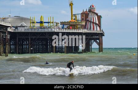 Brighton UK 19. Juni 2020 - Surfer versuchen an einem sonnigen, aber luftigen Nachmittag entlang der Südküste eine Welle am Brighton Palace Pier zu fangen. Das Wetter wird voraussichtlich viel wärmer werden nächste Woche mit Temperaturen voraussichtlich 30 Grad in Teilen des Südostens erreichen : Credit Simon Dack / Alamy Live News Stockfoto