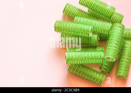 Haarauszieher auf dem rosa Hintergrund. Grüne Kulere für Frisur. Stockfoto