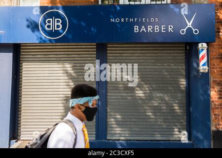 Mann mit Gesichtsmaske geht vorbei geschlossenen Friseur und Friseure mit geschlossenen Ladenfront während der Coronavirus-Pandemie, Ealing, West London Stockfoto