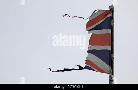 Union Jack, britische Flagge, zerfetzelt, gerissen, fliegen und flattern auf einem grauen Pfosten mit grauem Himmel könnte eine Katastrophe wie Krieg, Sturm oder Brexit illustrieren. Stockfoto