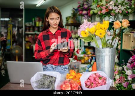 Asiatische Frau Florist Small Business Flower Shop Besitzer hält Rechner für die Arbeit, um Aufträge für ihr Geschäft nehmen. Stockfoto
