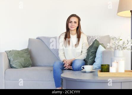 Entspannte Frau sitzt auf dem Sofa zu Hause Stockfoto