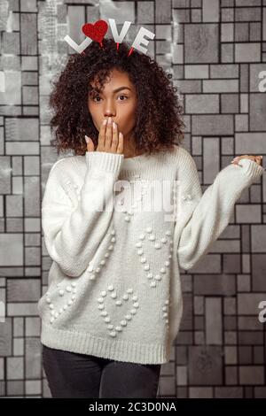 Nahaufnahme Porträt eines jungen afroamerikanischen Mädchens mit lockigem Haar in einem weißen Pullover Stockfoto