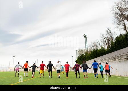 Barcelona, spanien - 20. juni 2020: Ein gemischtes Fußballteam während der Praxis Hände halten, die Schaffung von Gemeinschaft und soziale Integration mit Migranten jung Stockfoto