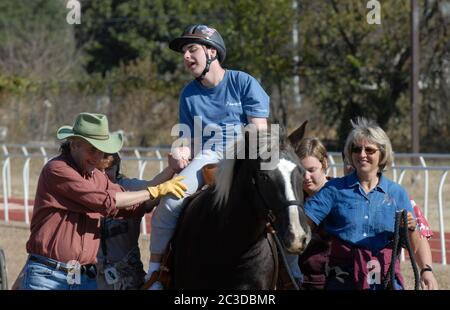 Austin, Texas, USA, 13. Dezember 2006: Ein Student, der die Texas School for the Blind and Visual Impaired (TSVBI) besucht, erlebt erstmals ein Reiten während eines Ausflugs in der Schule im Zentrum von Austin. Rancher bringen einmal im Jahr Pferde auf den Campus, um neue Erfahrungen zu machen und das Selbstbewusstsein von rechtlich blinden Studenten zu stärken. Stockfoto