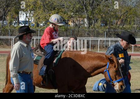 Austin, Texas, USA, 13. Dezember 2006: Ein Student, der die Texas School for the Blind and Visual Impaired (TSVBI) besucht, erlebt erstmals ein Reiten während eines Ausflugs in der Schule im Zentrum von Austin. Rancher bringen einmal im Jahr Pferde auf den Campus, um neue Erfahrungen zu machen und das Selbstbewusstsein von rechtlich blinden Studenten zu stärken. Stockfoto