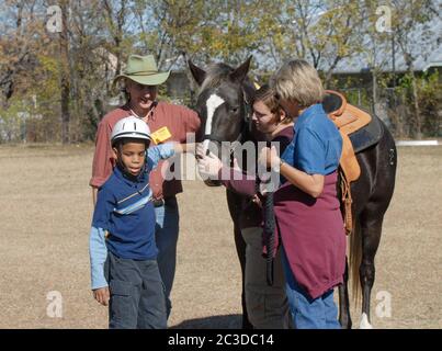 Austin, Texas, USA, 13. Dezember 2006: Ein Student, der die Texas School for the Blind and Visual Impaired (TSVBI) besucht, erlebt erstmals ein Reiten während eines Ausflugs in der Schule im Zentrum von Austin. Rancher bringen einmal im Jahr Pferde auf den Campus, um neue Erfahrungen zu machen und das Selbstbewusstsein von rechtlich blinden Studenten zu stärken. Stockfoto