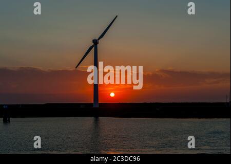 Die Sonne geht hinter einem Windgenerator (Windmühle) in der Nähe von Hoogerheide, einem Dorf in Nordbrabant, Niederlande, nahe der Grenze zu Belgien unter. Stockfoto