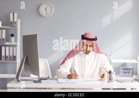 Ruhiger arabischer Mann sitzt an einem Tisch im Büro. A Stockfoto