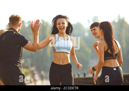 Die Läuferin macht Spaß mit einer Gruppe von Freunden in einem Park Stockfoto