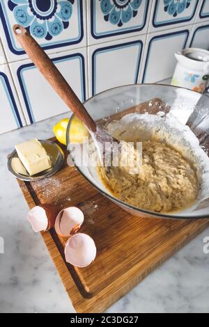 Glasschüssel voll von Kuchen Mischung, und Zutaten auf der Seite zu Biskuitkuchen zu machen. Butter, Eier und Zitrone Stockfoto