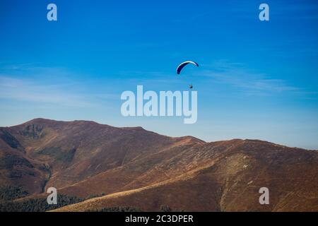 Gleitschirm fliegen über Berge Gipfel im Herbst Tag mit schönen Luftbild Welt. Freedom Lifestyle Konzept Stockfoto