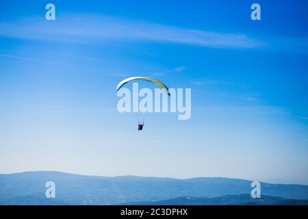 Paraglide Silhouette fliegen über Karpaten Berge auf blauem Himmel Hintergrund. Gefühl der Freiheit Stockfoto