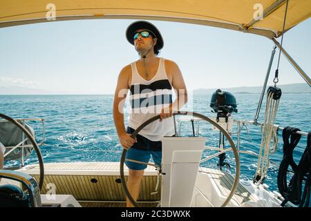 Männlicher Skipper am Lenkrad einer Yacht. Segel- und Segelkonzept. Stockfoto