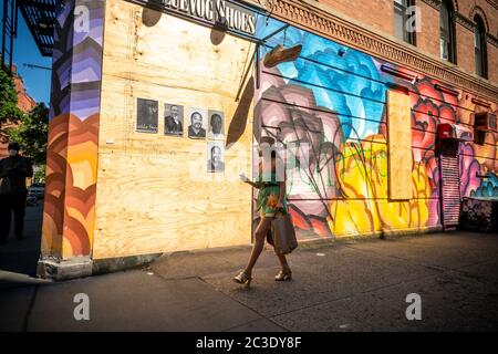 Frau ohne Maske geht an der aufgeketteten John Fluevog Schuhgeschäft in Nolita in New York vorbei sind wegen Plünderungen und Vandalisierung im Zusammenhang mit den Protesten im Zusammenhang mit dem Tod von George Floyd, gesehen am Samstag, 6. Juni 2020, verladen. (© Richard B. Levine) Stockfoto