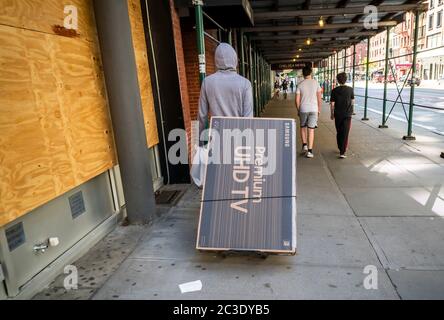 Der Kunde trägt seine Marke Samsung Flachbildschirm-Fernseher in Chelsea in New York am Samstag, 13. Juni 2020 als Geschäfte für Bordkügelabholung während Phase eins der Stadt Wiedereröffnung geöffnet. (© Richard B. Levine) Stockfoto