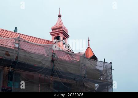 Gebäude im Bau. Das Gebäude ist mit Gerüsten bedeckt, außer dem Dach, das bereits hell neu ist. Stockfoto