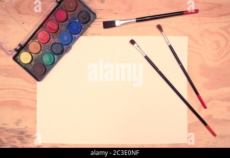 Flachlegen - Aquarelle, Pinsel, Papier, Holztisch (Vintage-Farbverschiebung) Stockfoto