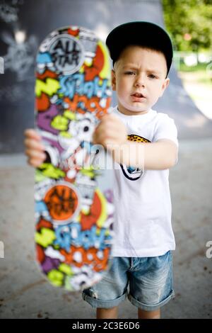 Junge mit einem Skate in einem Skatepark. Ein Junge mit Brille lernt skaten. Stockfoto