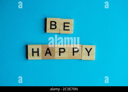 Holzblöcke mit Be Happy Words auf blauem Hintergrund Stockfoto