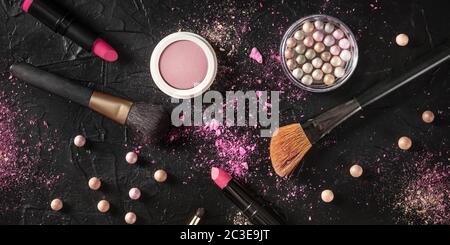 Professionelles Schminkpanorama auf schwarzem Hintergrund. Pinsel, Lippenstift und andere Produkte, ein flaches Lay mit einem Ort für Text Stockfoto