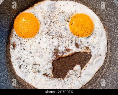 Nahaufnahme eines ungewöhnlichen Spiegelei mit zwei Eigelb ähnlich einem Emoticon Stockfoto