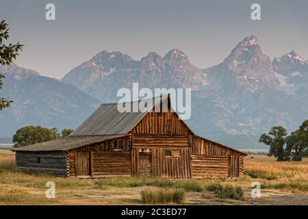 Morgensonnenaufgang über der T.A Molton Scheune im Mormon Row Historic District entlang der Antelope Flats mit den Grand Teton Bergen hinter dem Grand Teton National Park, Wyoming. Stockfoto