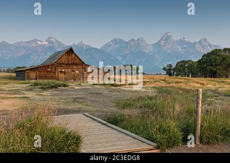 Morgensonnenaufgang über der T.A Molton Scheune im Mormon Row Historic District entlang der Antelope Flats mit den Grand Teton Bergen hinter dem Grand Teton National Park, Wyoming. Stockfoto