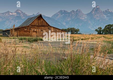 Morgensonnenaufgang über der T.A Molton Scheune im Mormon Row Historic District entlang der Antelope Flats mit den Grand Teton Bergen hinter dem Grand Teton National Park, Wyoming. Stockfoto