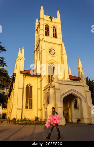 Shimla, Himachal Pradesh, Indien - Mai 2012: Ein Straßenhändler geht vorbei an der britischen Kolonialzeit neogotische Architektur der Christ Church, einer der o Stockfoto