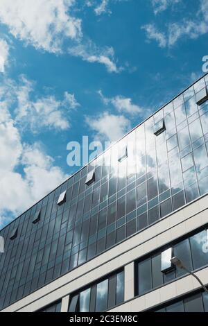 Modernes Firmengebäude mit Wolken, die sich im Glas spiegeln Stockfoto
