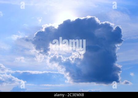 Wolke mit ungewöhnlicher Form und sonnigen Strahlen. Sonne spätet aus hinter dunkler Wolke. Sonnenstrahlen in trüb Stockfoto