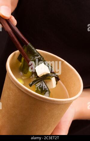 Frau, die Miso-Suppe in Öko-Tasse isst. Stockfoto