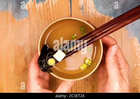 Frau, die Miso-Suppe in Öko-Tasse isst. Stockfoto