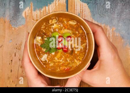 Frau hält heiße und saure Suppe in Öko-Tasse. Stockfoto