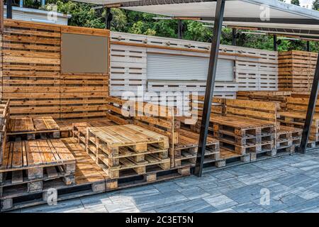 Holzbank aus Paletten von Frachtschüllen zum Sitzen. Kreative Outdoor-Café-Tisch und Bänke. Konzeptionelle Stühle und Tische. Moderne urbane l Stockfoto