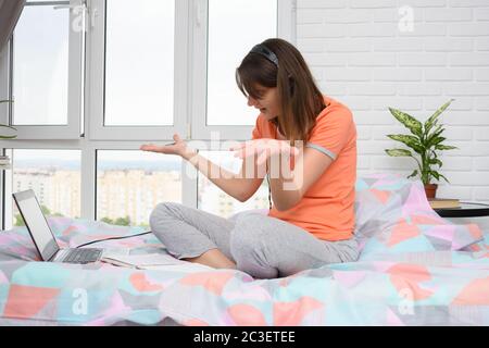 Das Mädchen spreizte überrascht die Hände und schaut neugierig auf den Bildschirm Stockfoto