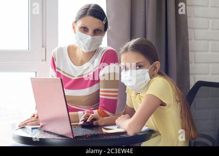 Die Familie, die in der Isolationsstation unter Quarantäne gestellt wurde, Mutter und Tochter, die Hausaufgaben machten, blickten in den Rahmen Stockfoto